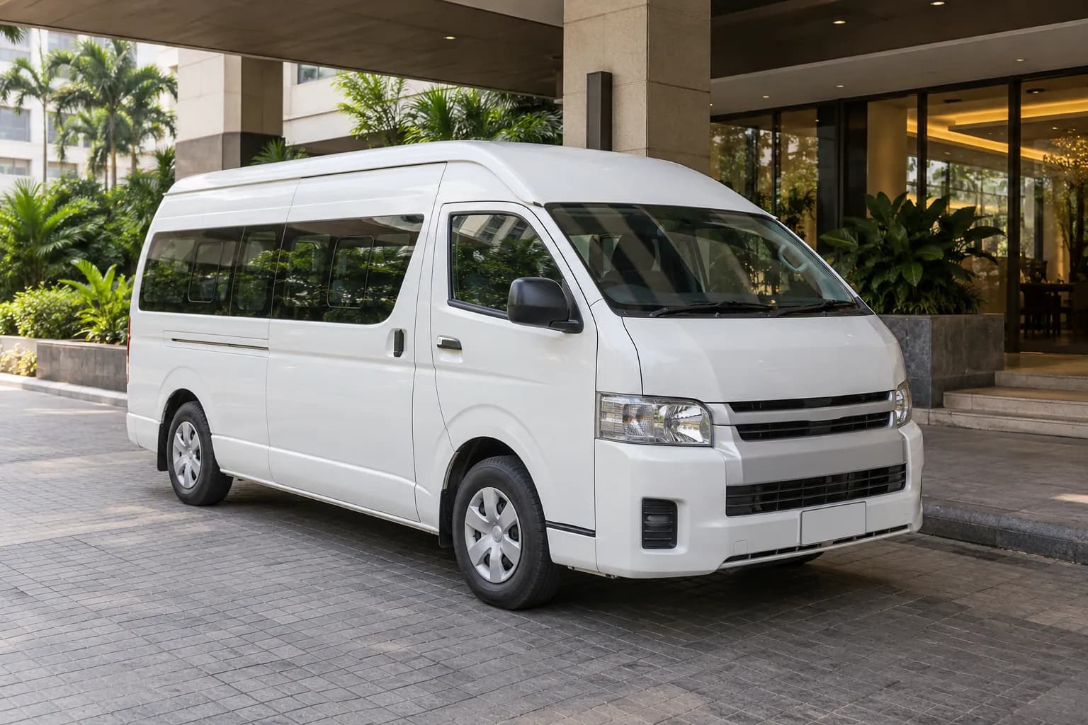 White passenger van parked at a tropical city hotel entrance